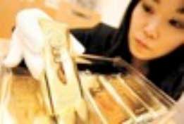 Photo of a woman inspecting gold bars